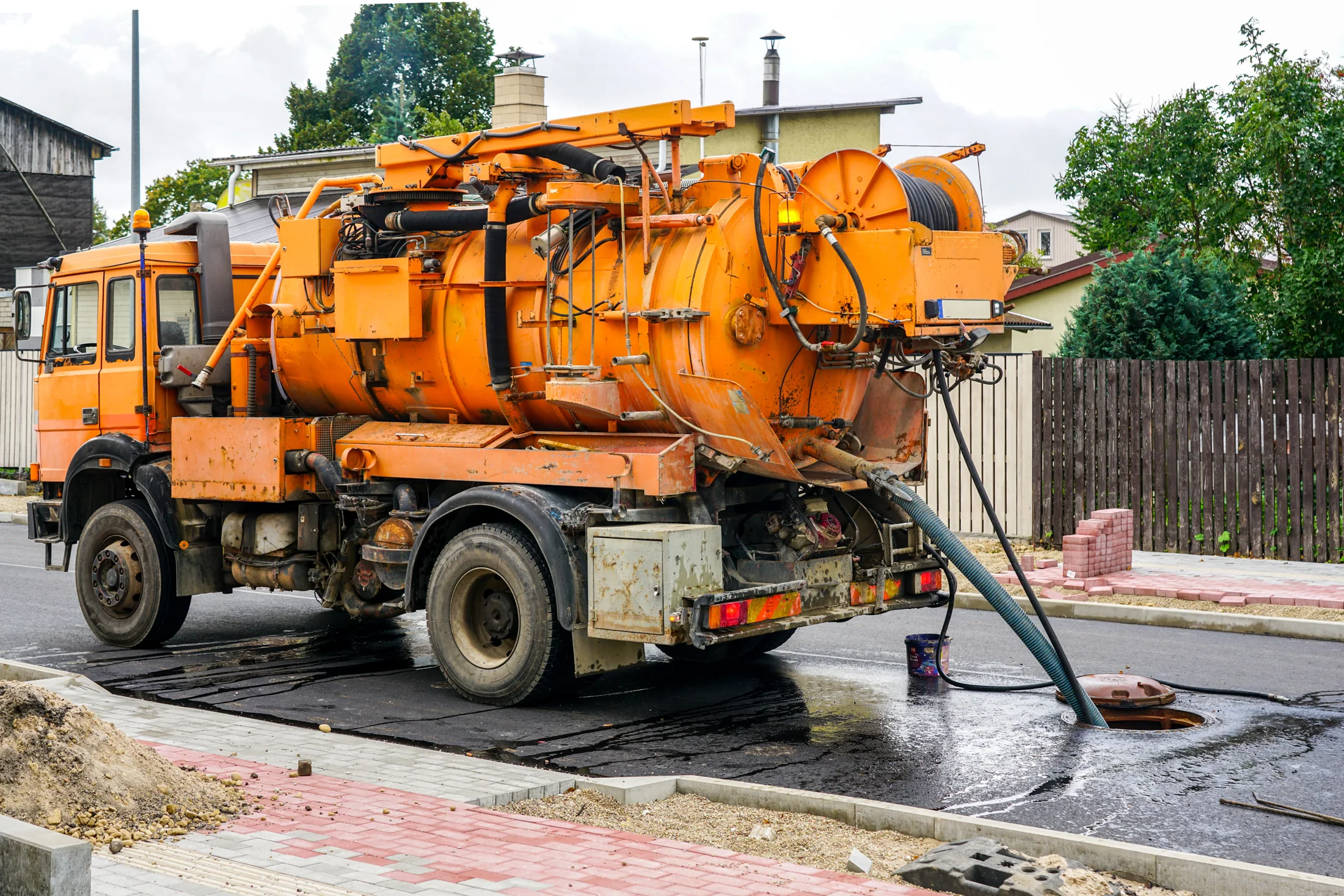 Combined vacuum and drain jetting truck at a road worksite.