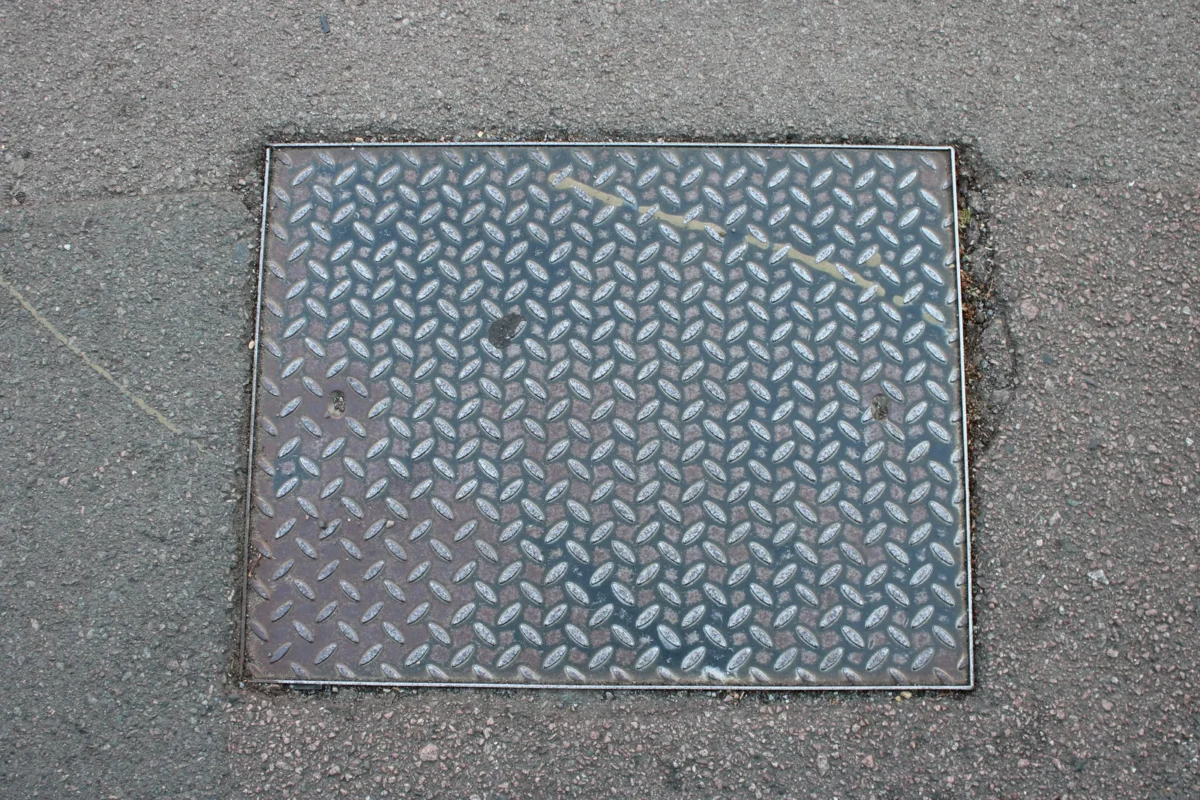 Metal inspection cover set into a public pavement in the UK.