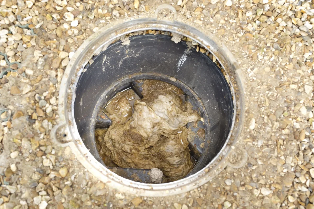 Solid debris obstructing an open sewer access point.